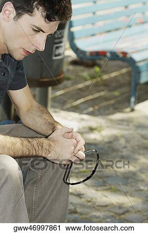 Close-up of a young man sitting on a bench View Large Photo Image Stock Image - Close-up of a young man sitting on a bench. Fotosearch