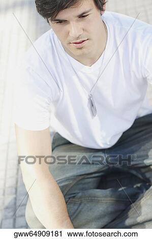 Close-up of a young man sitting on the floor View Large Photo Image Stock Image - Close-up of a young man sitting on the floor. Fotosearch