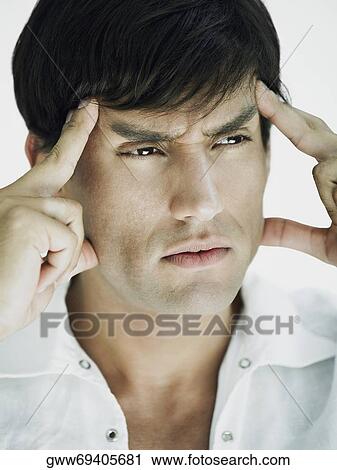 Stock Image - Close-up of a young man suffering from a headache. Fotosearch