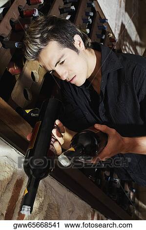 Close-up of a young man taking a bottle from a wine rack View Large Photo Image Stock Image - Close-up of a young man taking a bottle from a wine rack. Fotosearch