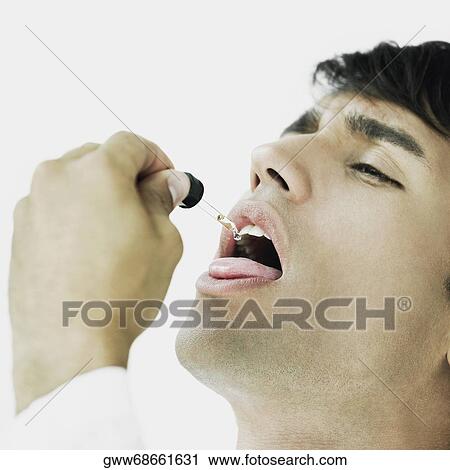 Close-up of a young man taking medicine with a dropper View Large Photo Image Stock Image - Close-up of a young man taking medicine with a dropper. Fotosearch