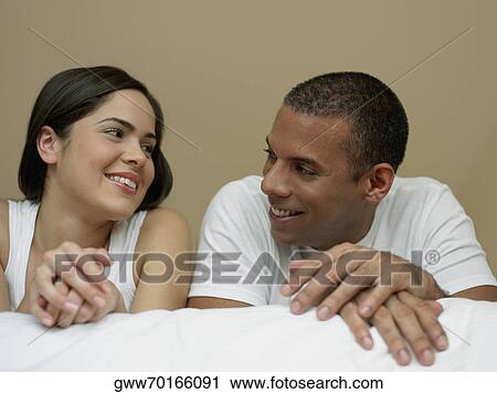 Close-up of a young woman and a mid adult man looking at each other and smiling View Large Photo Image Stock Image - Close-up of a young woman and a mid adult man looking at each other and smiling. Fotosearch
