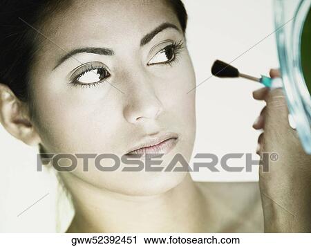 Close-up of a young woman applying make-up with a make-up brush View Large Photo Image Stock Image - Close-up of a young woman applying make-up with a make-up brush. Fotosearch