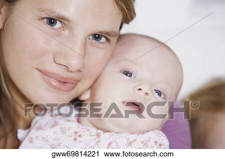 Stock Image - Close-up of a young woman carrying her baby girl. Fotosearch