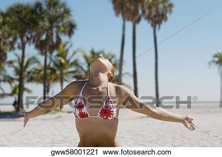 Stock Image - Close-up of a young woman exercising on the beach. Fotosearch