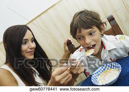 Stock Image - Close-up of a young woman feeding her son. Fotosearch