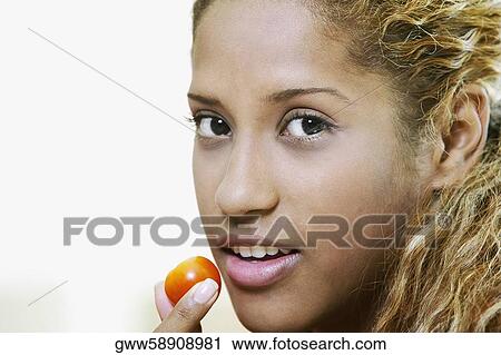 Close-up of a young woman holding a cherry in front of her mouth View Large Photo Image Stock Image - Close-up of a young woman holding a cherry in front of her mouth. Fotosearch