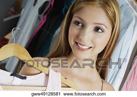Close-up of a young woman holding a top on a hanger View Large Photo Image Stock Image - Close-up of a young woman holding a top on a hanger. Fotosearch