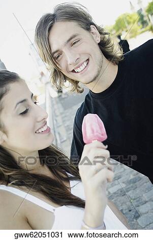 Close-up of a young woman holding an ice-cream with a teenage boy smiling View Large Photo Image Stock Image - Close-up of a young woman holding an ice-cream with a teenage boy smiling. Fotosearch