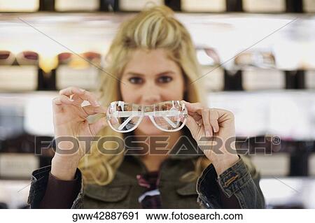 Stock Image - Close-up of a young woman holding sunglasses in a store. Fotosearch