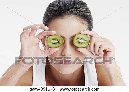 Close-up of a young woman holding slices of kiwi fruit in front of her eyes View Large Photo Image Stock Image - Close-up of a young woman holding slices of kiwi fruit in front of her eyes. Fotosearch