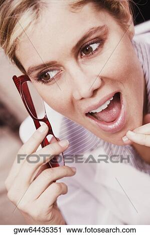Stock Image - Close-up of a young woman holding eyeglasses. Fotosearch