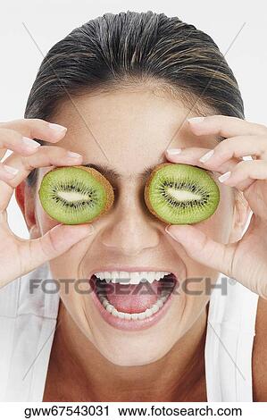 Close-up of a young woman holding slices of kiwi fruit in front of her eyes and laughing View Large Photo Image Stock Image - Close-up of a young woman holding slices of kiwi fruit in front of her eyes and laughing. Fotosearch