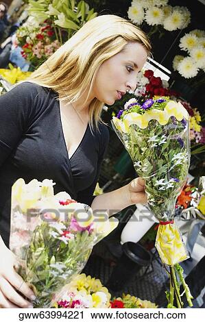 Stock Image - Close-up of a young woman holding two bouquets of flowers. Fotosearch