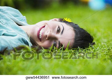 Stock Image - Close-up of a young woman lying on her back in a park. Fotosearch