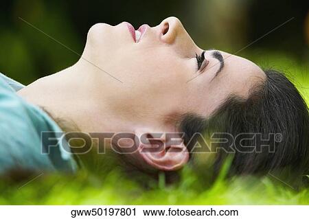 Close-up of a young woman lying on the grass View Large Photo Image Stock Image - Close-up of a young woman lying on the grass. Fotosearch