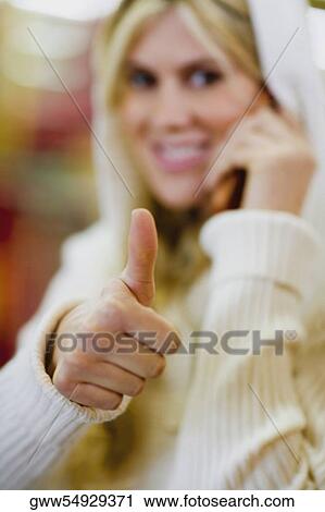 Close-up of a young woman making a thumbs up sign View Large Photo Image Stock Image - Close-up of a young woman making a thumbs up sign. Fotosearch