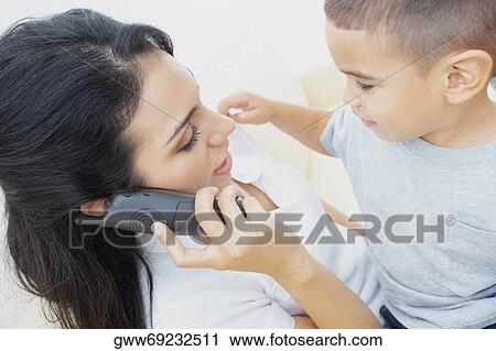 Close-up of a young woman on the phone and her son sitting on her lap View Large Photo Image Stock Image - Close-up of a young woman on the phone and her son sitting on her lap. Fotosearch