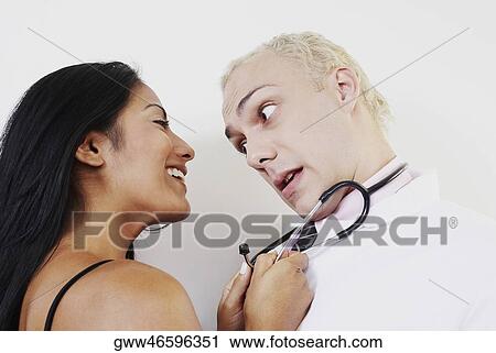 Stock Image - Close-up of a young woman pulling male doctor with a stethoscope. Fotosearch