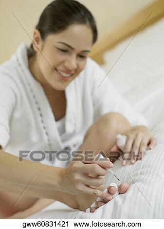 Stock Image - Close-up of a young woman sitting and polishing her nails. Fotosearch