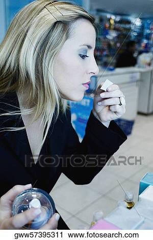 Stock Image - Close-up of a young woman smelling perfume in a store. Fotosearch