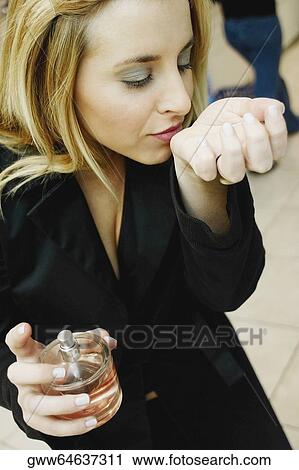 Close-up of a young woman smelling perfume in a store View Large Photo Image Stock Image - Close-up of a young woman smelling perfume in a store. Fotosearch