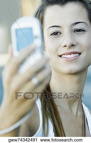 Stock Image - Close-up of a young woman taking a photograph of herself. Fotosearch