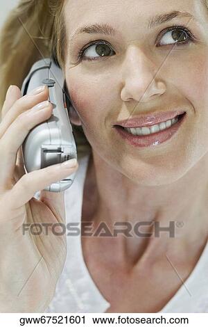 Stock Image - Close-up of a young woman talking on a cordless phone. Fotosearch