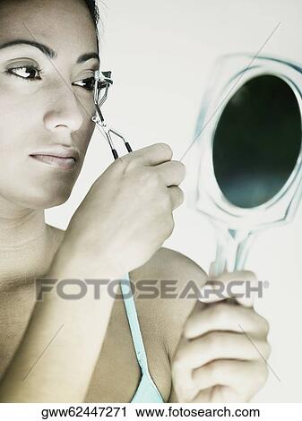 Close-up of a young woman using an eyelash curler View Large Photo Image Stock Image - Close-up of a young woman using an eyelash curler. Fotosearch