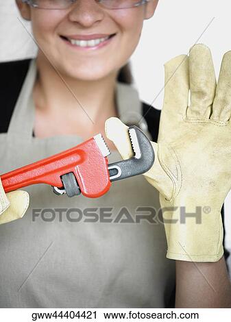 Stock Image - Close-up of a young woman with her thumb in an adjustable wrench. Fotosearch