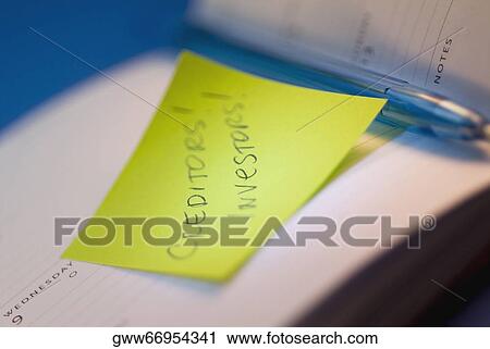 Stock Image - Close-up of an adhesive note and a pen in an open diary. Fotosearch