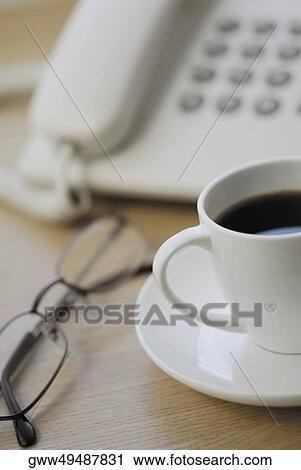 Close-up of eyeglasses and a tea cup in front of a telephone View Large Photo Image Stock Image - Close-up of eyeglasses and a tea cup in front of a telephone. Fotosearch