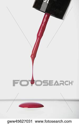 Stock Image - Close-up of nail polish liquid dripping from a brush. Fotosearch