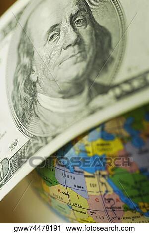Stock Image - Close-up of one hundred US dollar bill on a globe. Fotosearch