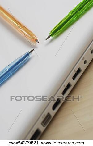 Stock Image - Close-up of three ballpoint pens on a laptop. Fotosearch