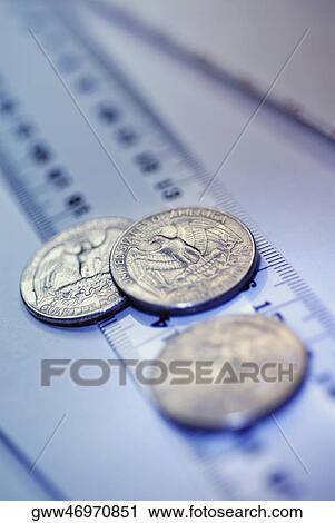 Stock Image - Close-up of three US coins on a ruler. Fotosearch