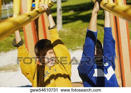Stock Image - Close-up of two brothers hanging on a jungle gym. Fotosearch