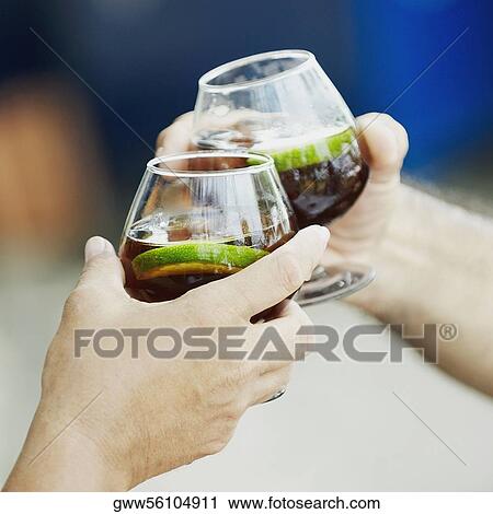 Stock Image - Close-up of two hands toasting with wine glasses. Fotosearch