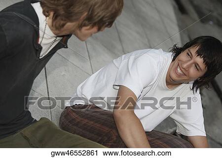 Stock Image - Close-up of two teenage boys sitting together and smiling. Fotosearch
