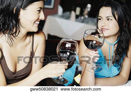 Close-up of two young women holding glasses of wine and smiling View Large Photo Image Stock Image - Close-up of two young women holding glasses of wine and smiling. Fotosearch