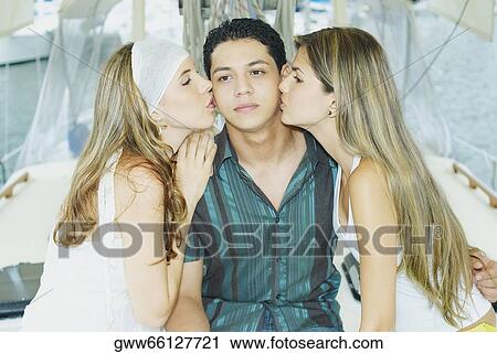 Close-up of two young women kissing a young man View Large Photo Image Stock Image - Close-up of two young women kissing a young man. Fotosearch