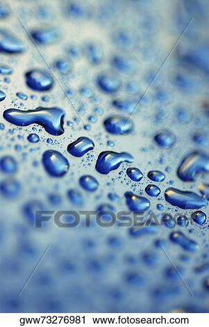 Stock Image - Close-up of water droplets on a blue surface. Fotosearch