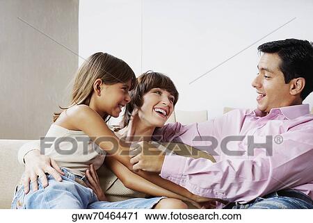 Couple sitting with their daughter and smiling View Large Photo Image Stock Image - Couple sitting with their daughter and smiling. Fotosearch