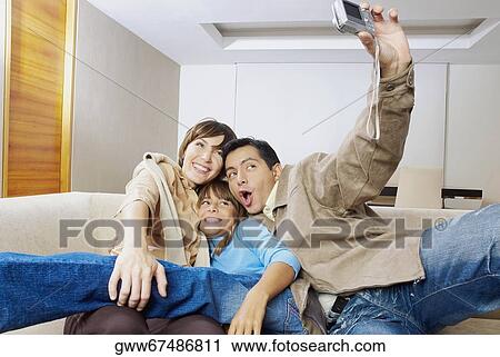 Stock Image - Couple with their daughter taking a photograph of themselves. Fotosearch