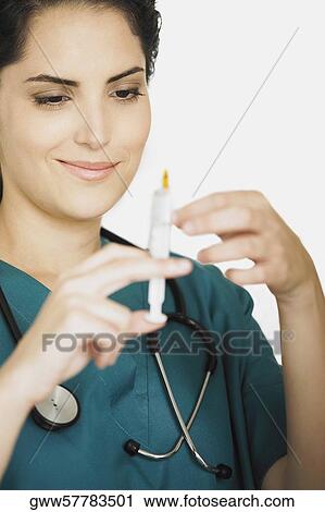 Female doctor holding and looking at a syringe View Large Photo Image Stock Image - Female doctor holding and looking at a syringe. Fotosearch