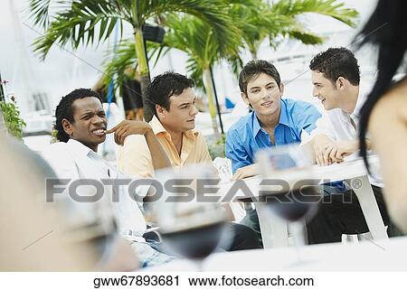 Four young men sitting in a restaurant View Large Photo Image Stock Image - Four young men sitting in a restaurant. Fotosearch