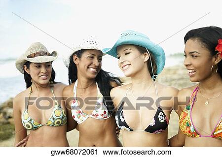 Four young women standing with their arms around each other on the beach View Large Photo Image Stock Image - Four young women standing with their arms around each other on the beach. Fotosearch