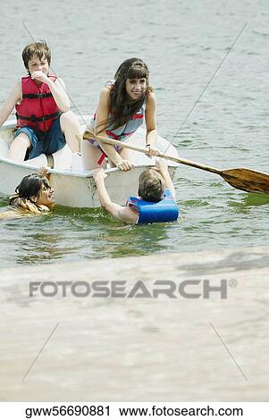 Girl in a boat with her friends swimming beside her View Large Photo Image Stock Image - Girl in a boat with her friends swimming beside her. Fotosearch