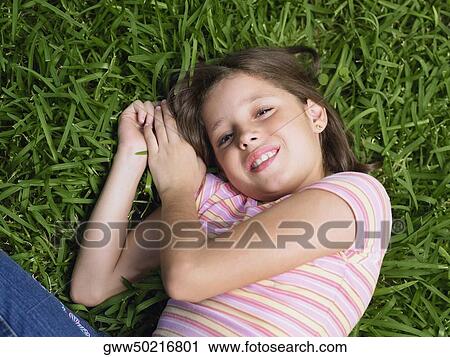 Stock Image - Girl smiling and lying on the grass. Fotosearch