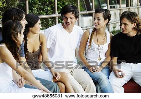 Group of friends sitting on a ledge View Large Photo Image Stock Image - Group of friends sitting on a ledge. Fotosearch
